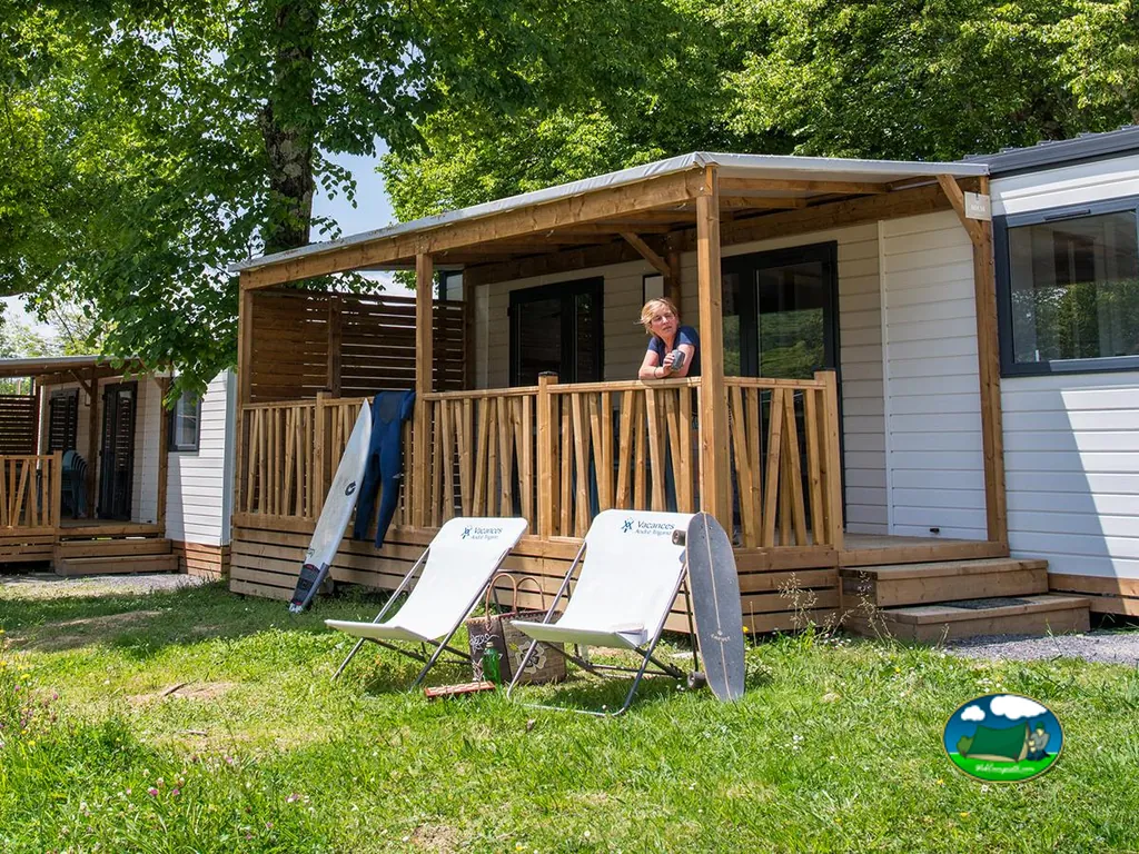 mobile home con porche de madera, tablas de surf y una mujer asomada a la barandilla en Hendaya