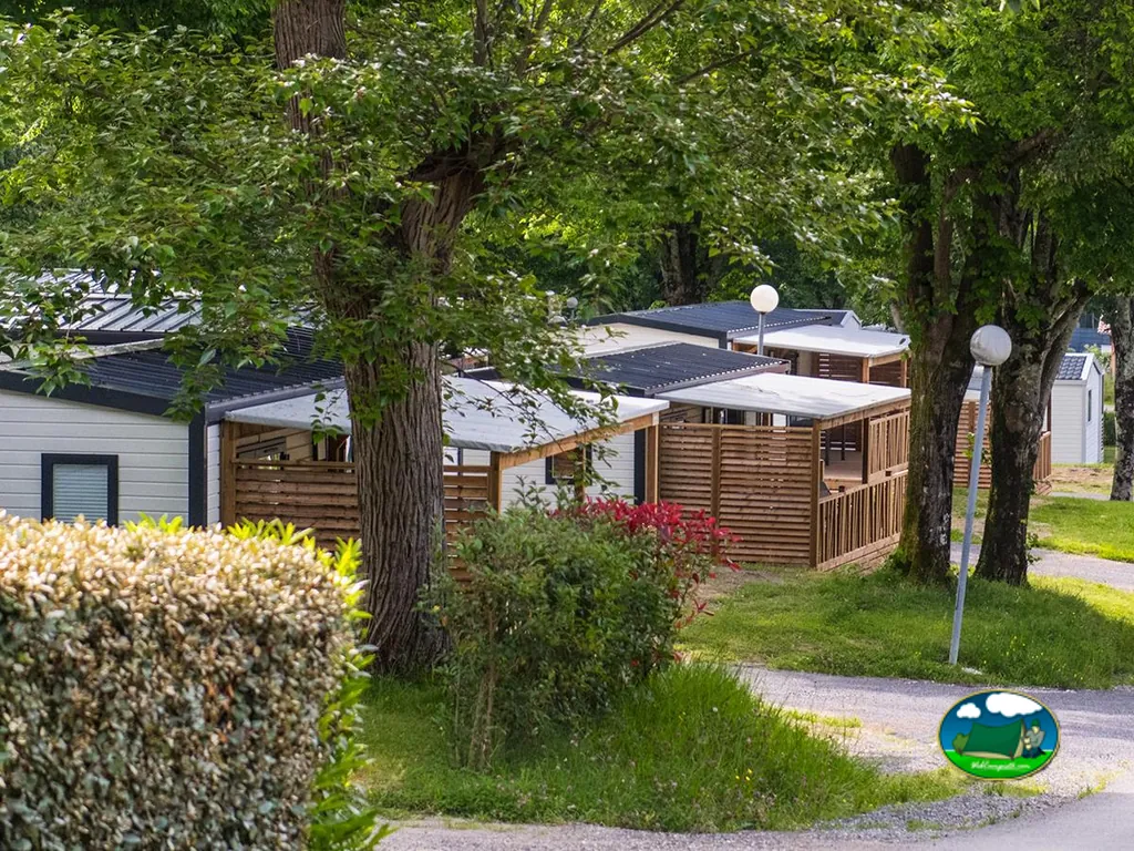 hilera de bungalows con porches de madera entre árboles en el camping de Hendaya