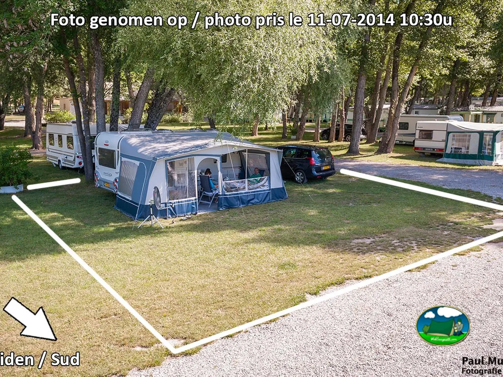 parcela delimitada con caravana y avancé bajo los árboles, foto de referencia con marcas de orientación superpuestas