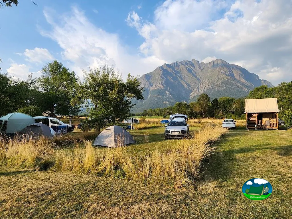 parcelas con tiendas y coches frente a una montaña rocosa en el camping Le Champ des Cimes de Aubessagne