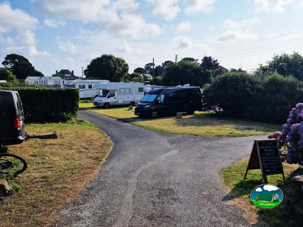 autocaravanas aparcadas en el camino de un camping junto a setos y casas cercanas en Ploubazlanec