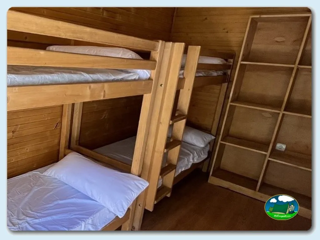 Cabaña interior con literas de madera y almacenaje del Camping La Devesa Aventura, Bembibre (León)