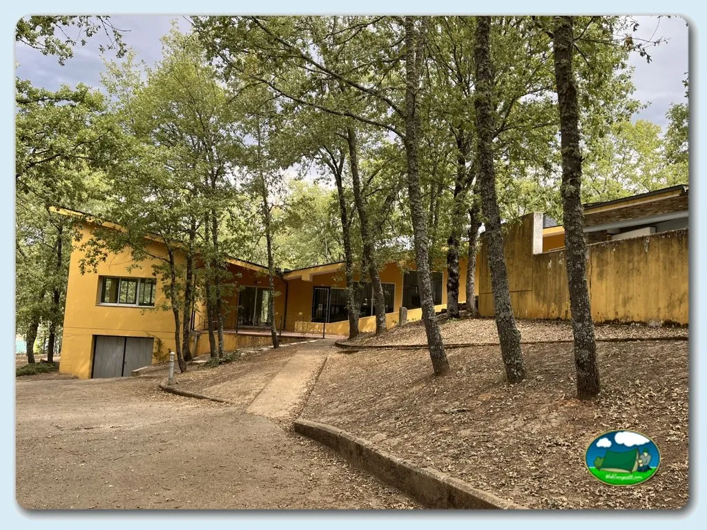 Cabaña amarilla entre árboles con aparcamiento del Camping La Devesa Aventura, Bembibre (León)