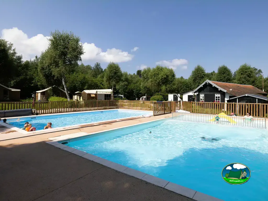 familias bañándose en las piscinas exteriores rodeadas de césped y chalets en Corcieux