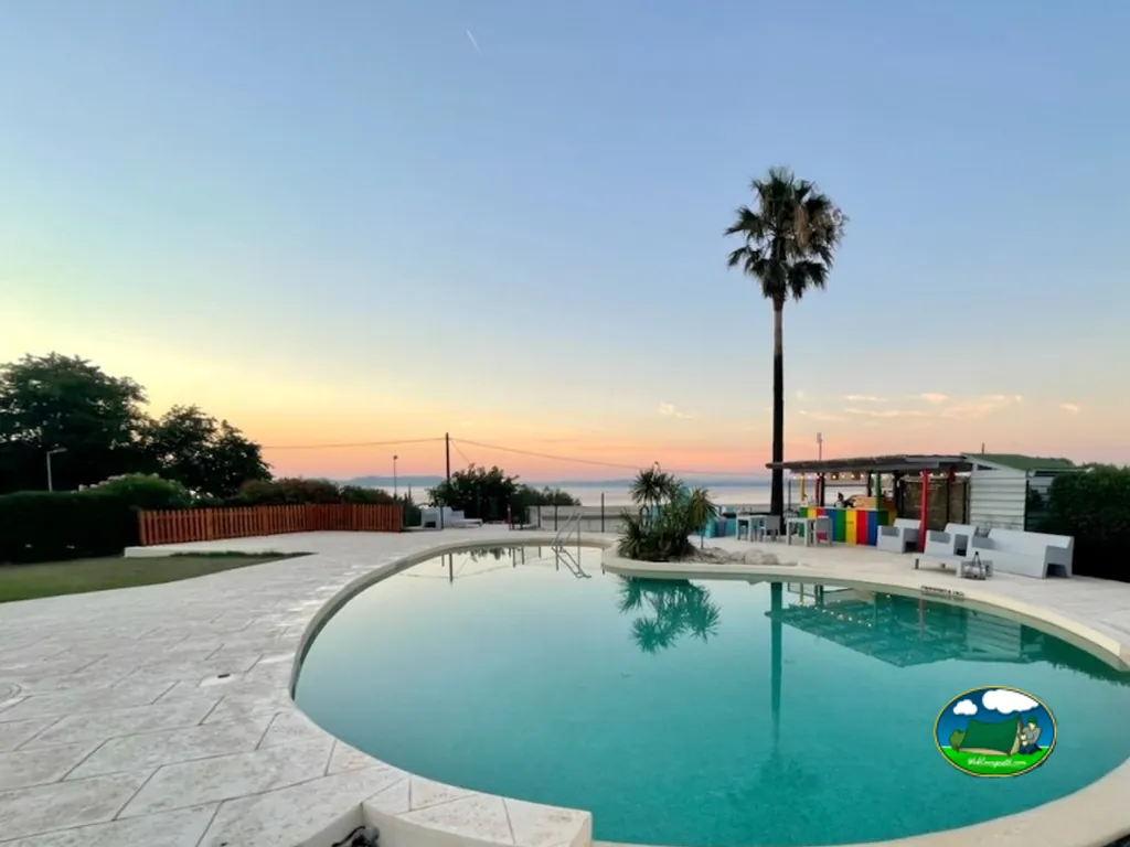 piscina redondeada con palmera y vistas al mar al atardecer en Saint-Mitre-les-Remparts