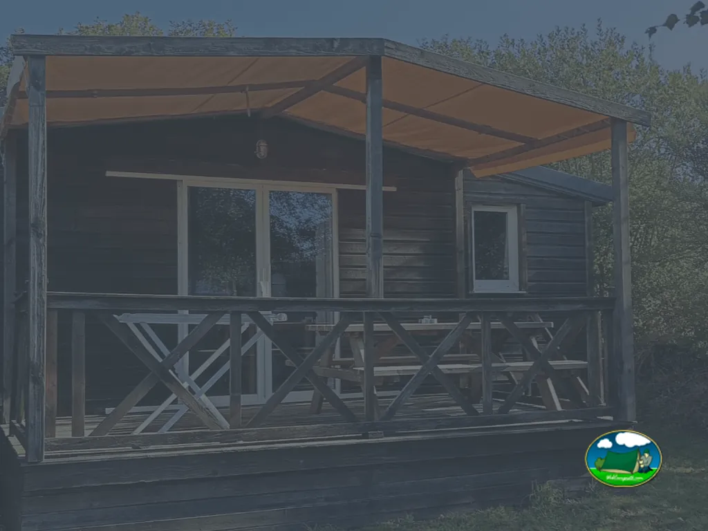 casa de madera con terraza cubierta y mesa de picnic, foto muy oscura