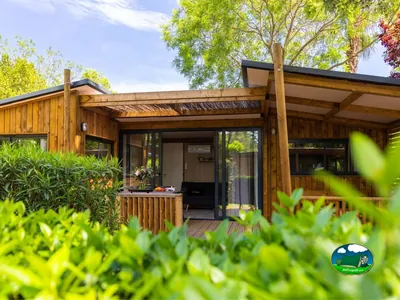 chalet de madera con porche cubierto y mesa entre vegetación en Saint-Cyprien