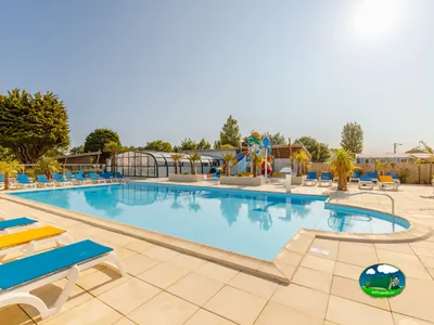piscina con tobogán multicolor y tumbonas azules vacías junto a palmeras