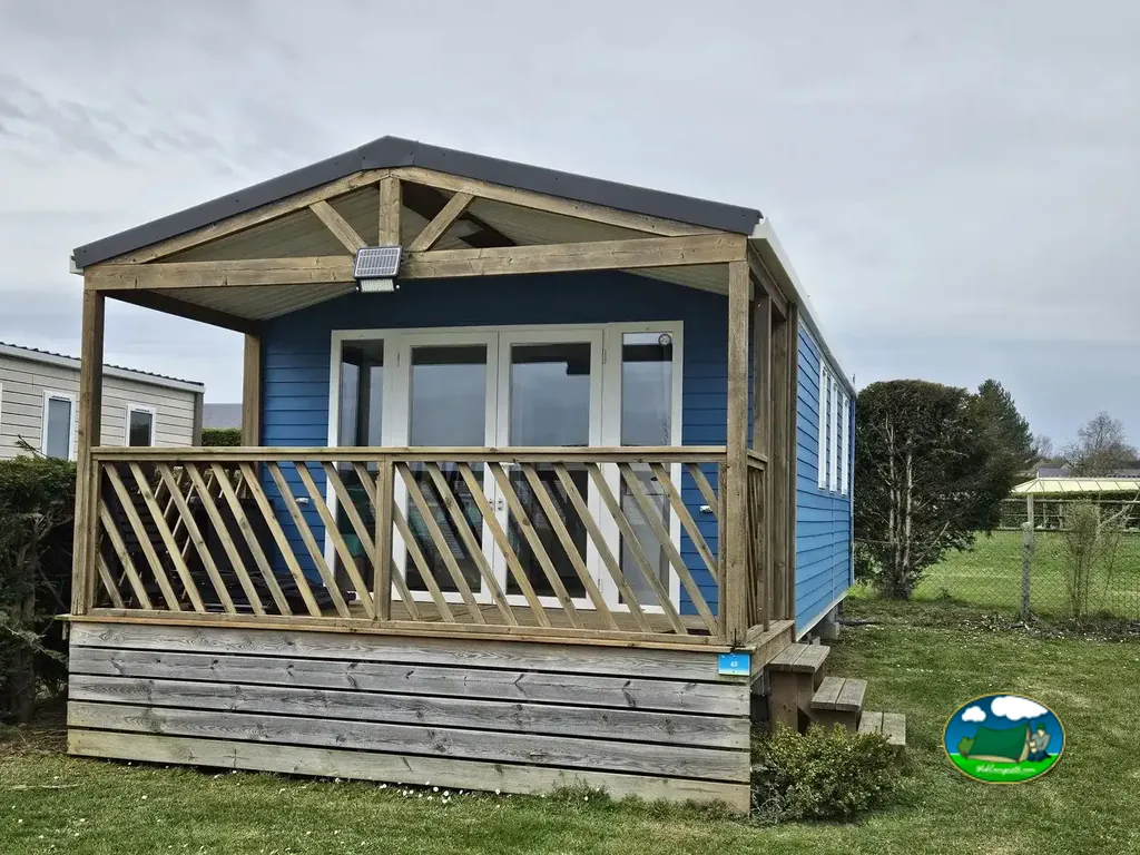 chalet azul con terraza de madera cubierta en Saint-Jouin-Bruneval