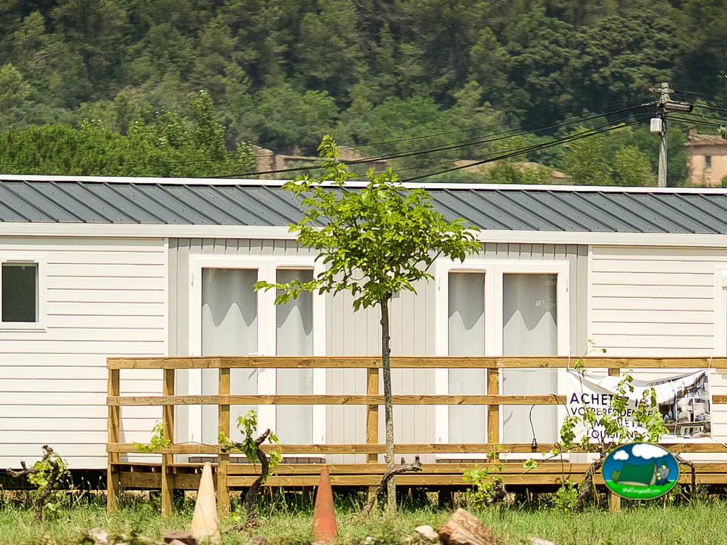 fila de mobil-homes tras un árbol con colina boscosa al fondo en Vidauban