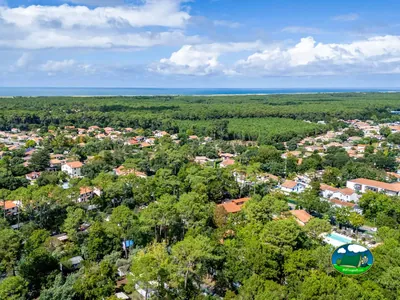 vista aérea del pinar con la piscina del camping asomando entre los árboles y el mar al fondo en Ondres