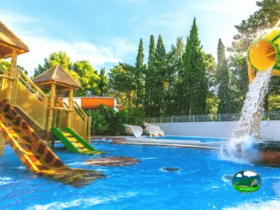 zona infantil de piscina con toboganes temáticos de jirafa y cascada de agua en Le Barcarès