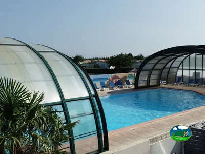 piscina cubierta con techo retráctil, tumbonas azules y mural decorativo en la pared del fondo