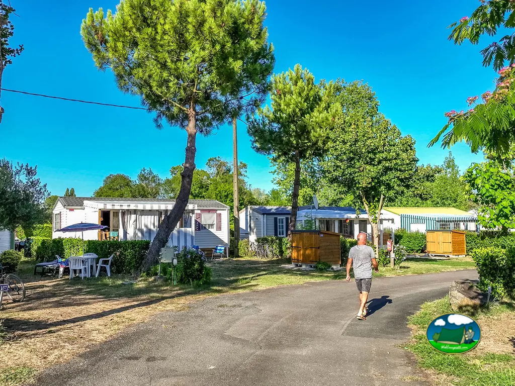 camino asfaltado entre casas móviles y arbolado con un hombre paseando en Notre-Dame-de-Monts