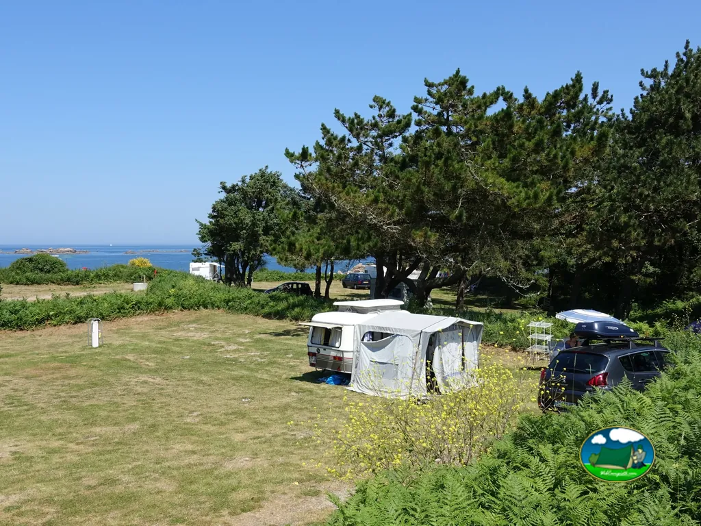 caravana con toldo en una parcela junto al mar entre pinos en Pleumeur-Bodou