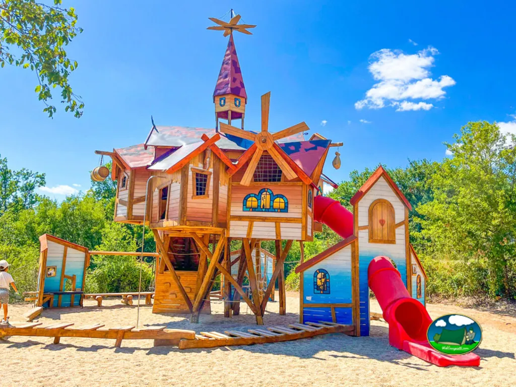 castillo de madera con tobogán rojo en la zona infantil del camping en Souillac
