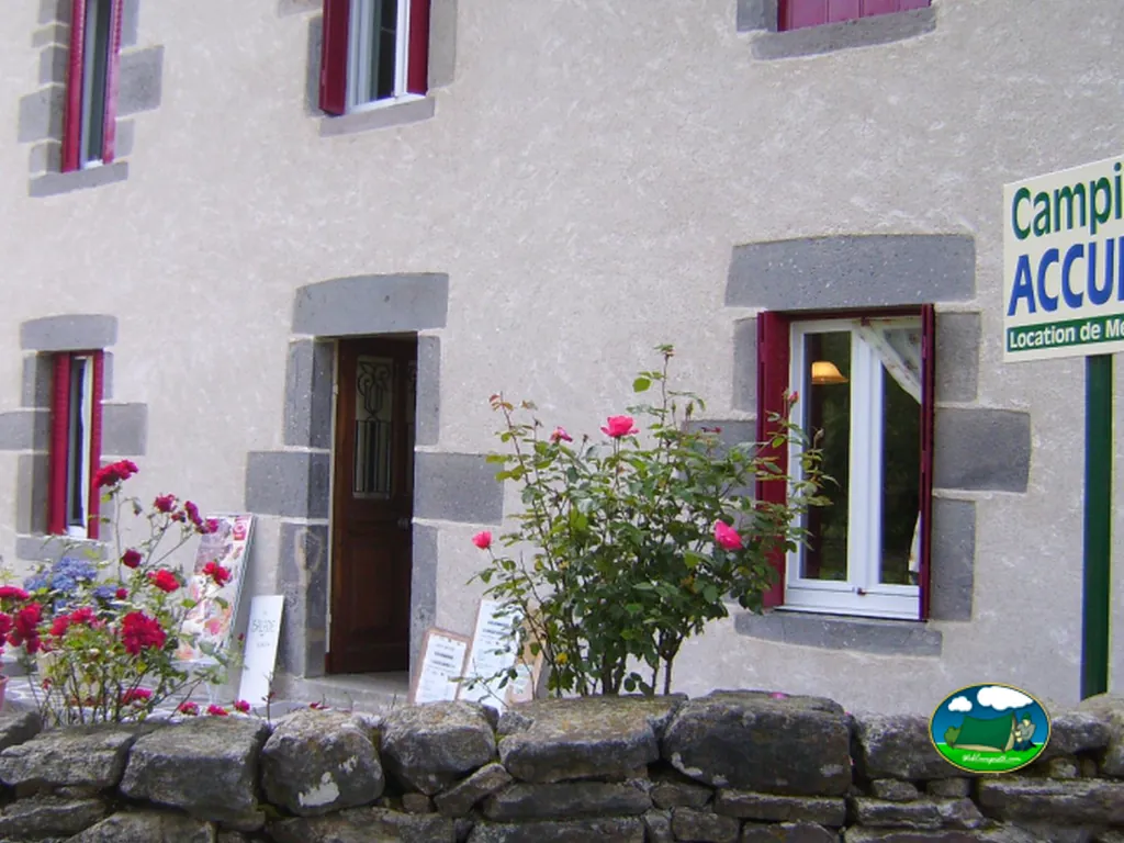 fachada de piedra de la recepción del camping con rosales en Chambon-sur-Lac
