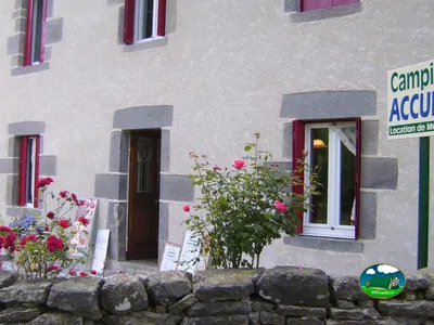 fachada de piedra de la recepción del camping con rosales en Chambon-sur-Lac