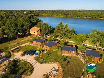 vista aérea de cabañas de madera y una casa en el árbol junto a un lago en La Guyonnière