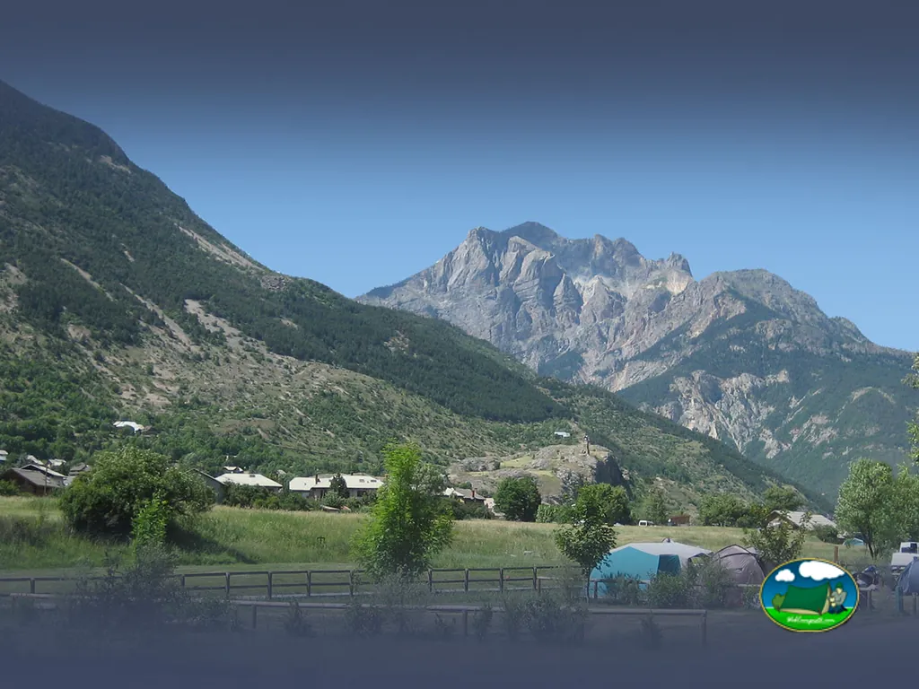 vista de la sierra de los Écrins con tiendas de campaña y una caravana en primer plano en L'Argentière-la-Bessée