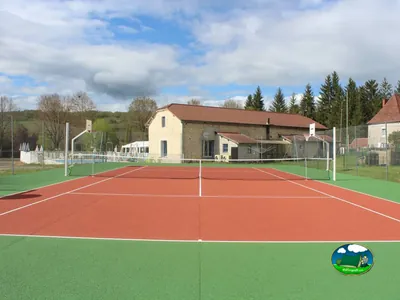 pista de tenis con piscina y edificio principal de piedra al fondo en Saint-Chamarand