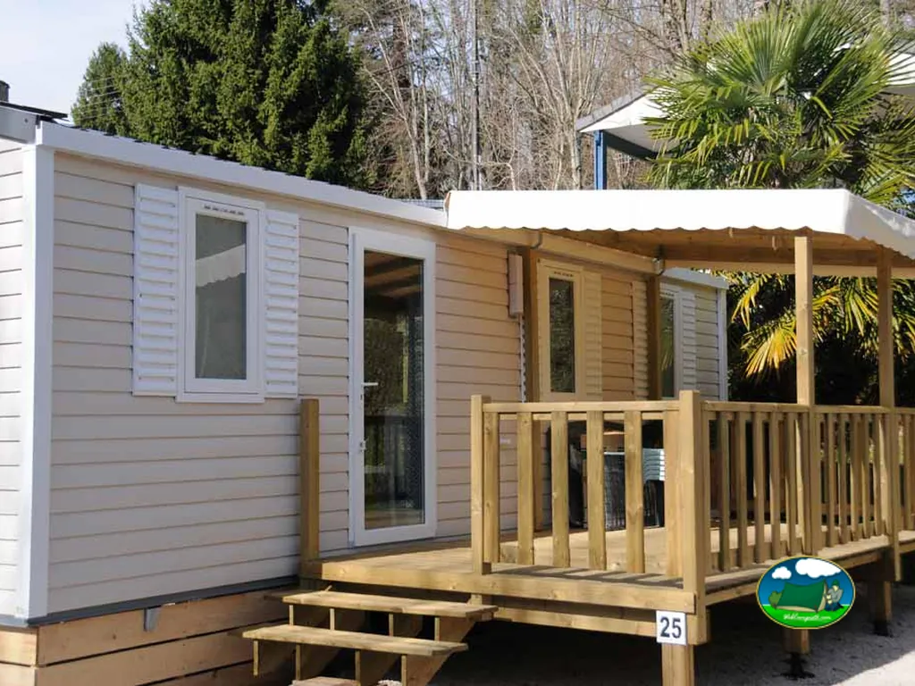 mobil-home con terraza de madera y palmeras junto al bosque en Capvern