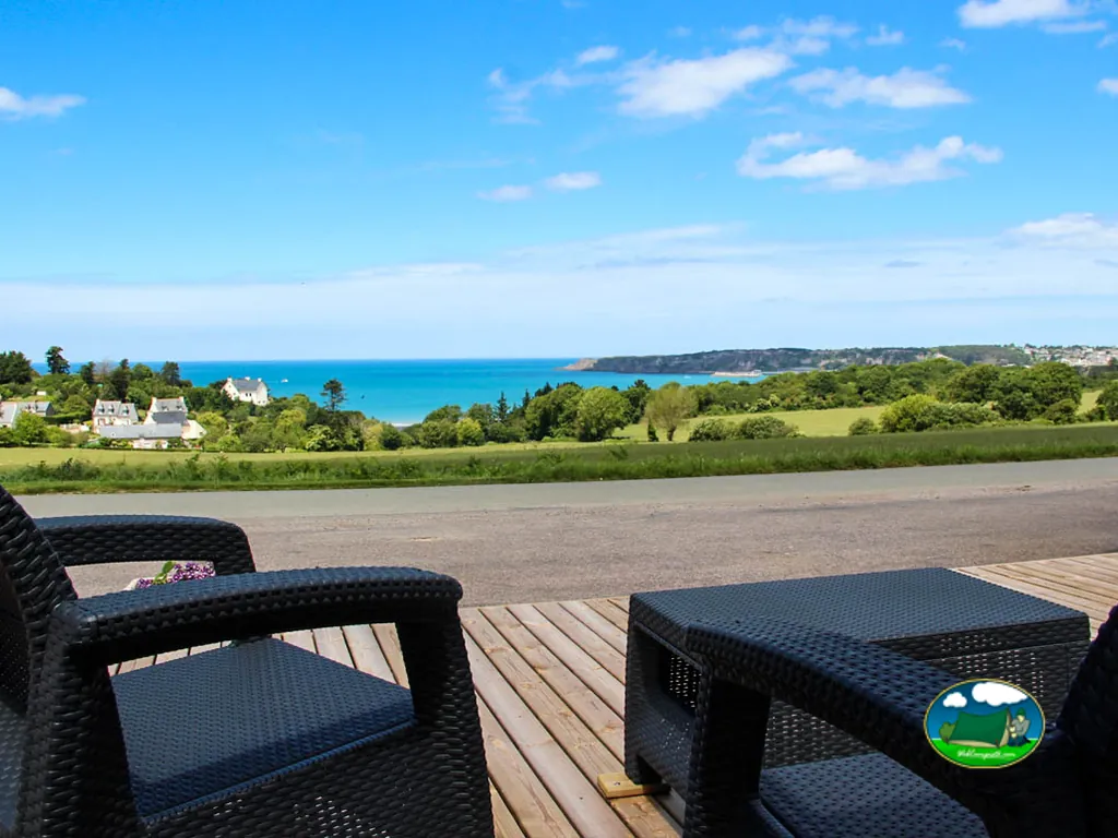 terraza con mobiliario de ratán oscuro y vistas al mar y la costa en Erquy