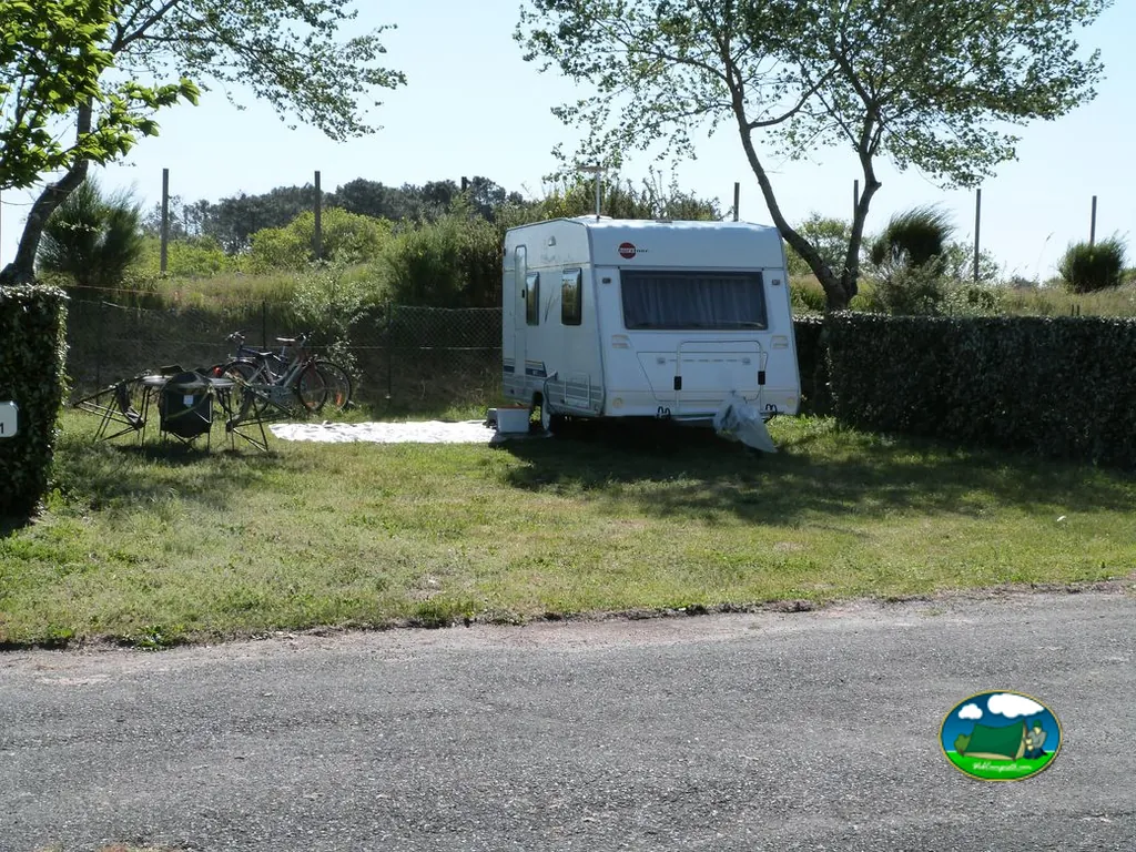caravana blanca en una parcela de césped con bicicletas y mesa de camping en Gujan-Mestras