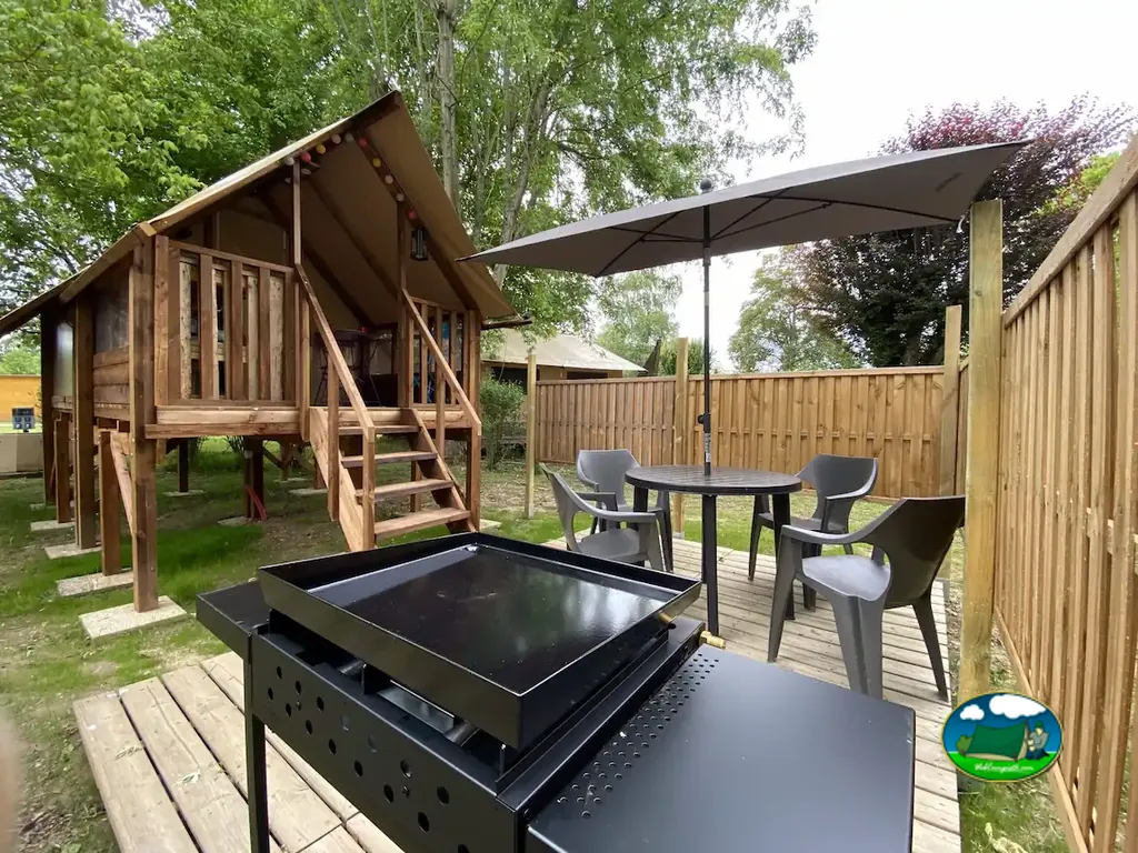 cabaña de camping glamping elevada con terraza de madera, mesa y barbacoa en Puybrun