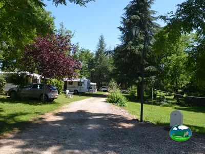 camino arbolado del camping con caravanas y autocaravanas estacionadas en Touzac