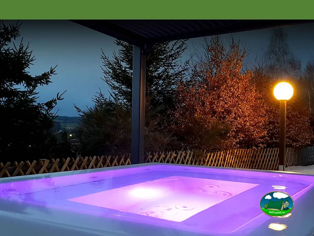 jacuzzi iluminado en tonos violeta bajo un porche al anochecer en el camping
