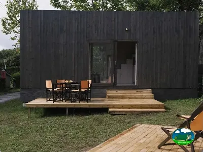 Glamping cabaña negra con terraza de madera y zona de comedor del Camping wecamp Cudillero, Cudillero (Asturias)