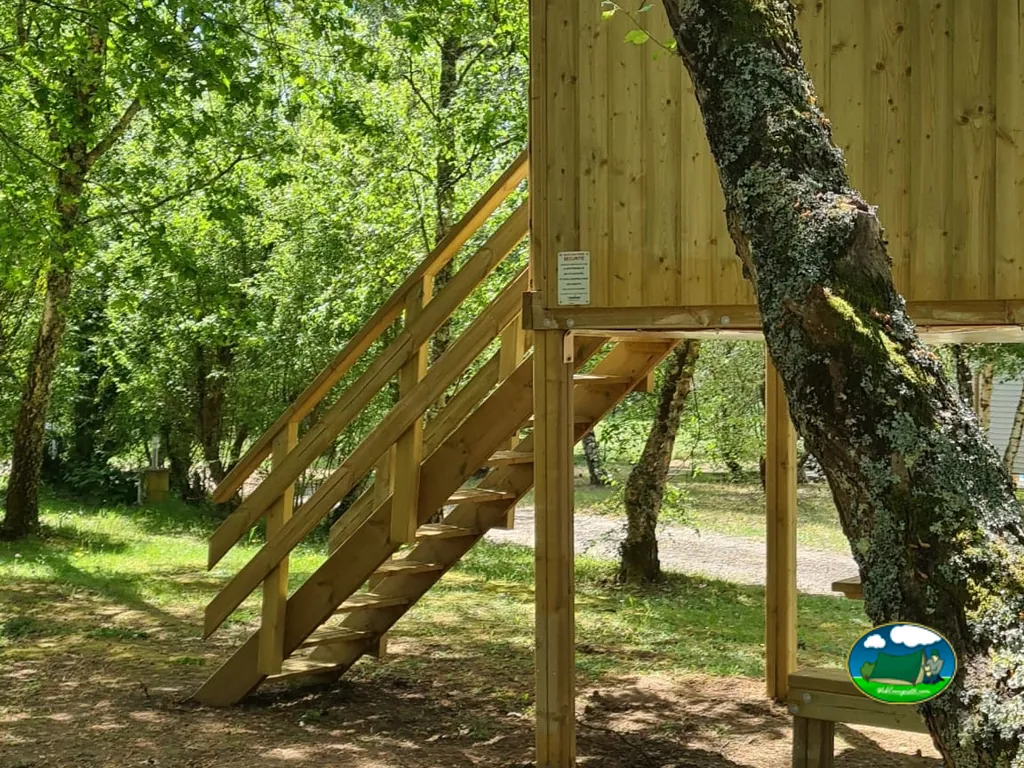 escalera de madera hacia una cabaña elevada entre árboles en Bayas