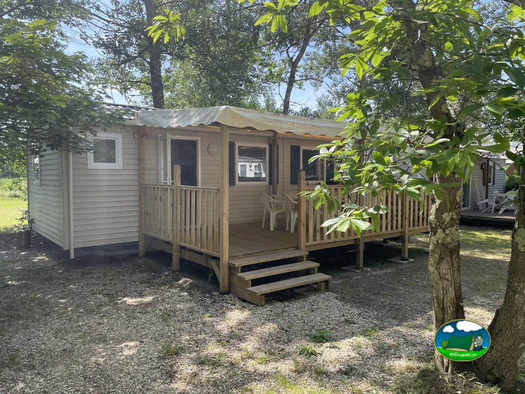 mobile home con porche techado y sillas bajo los árboles en Bayas