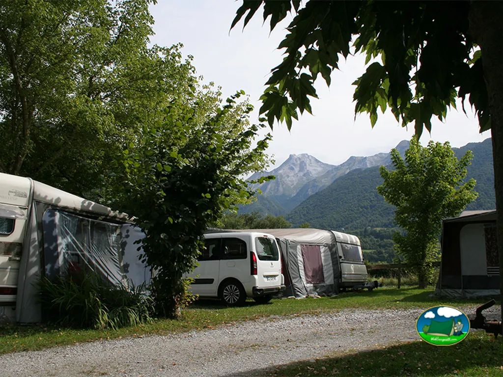 parcelas de caravanas con toldos y furgoneta ante las montañas de Laruns