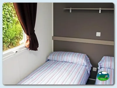 Bungalow dormitorio con ventana y vistas al jardín del Camping Las Gaviotas, Santa María del Mar (Asturias)