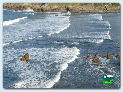 Playa junto al mar con acantilados y olas del Camping Las Gaviotas, Santa María del Mar (Asturias)