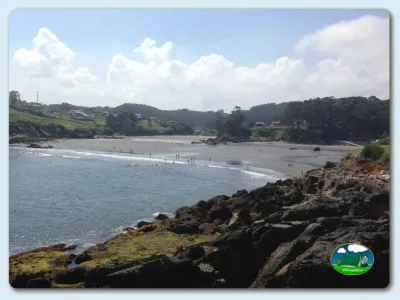 Playa junto al mar con montaña y bungalows del Camping Las Gaviotas, Santa María del Mar (Asturias)