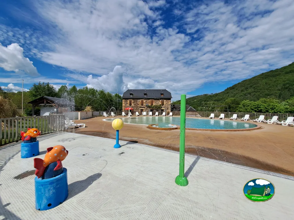 piscina con juegos de agua infantiles frente al edificio principal en Saint-Geniez-d'Olt
