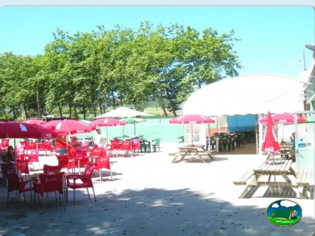 Restaurante con sombrillas rojas y vistas a la montaña del Camping El Molino, Gozón (Asturias)