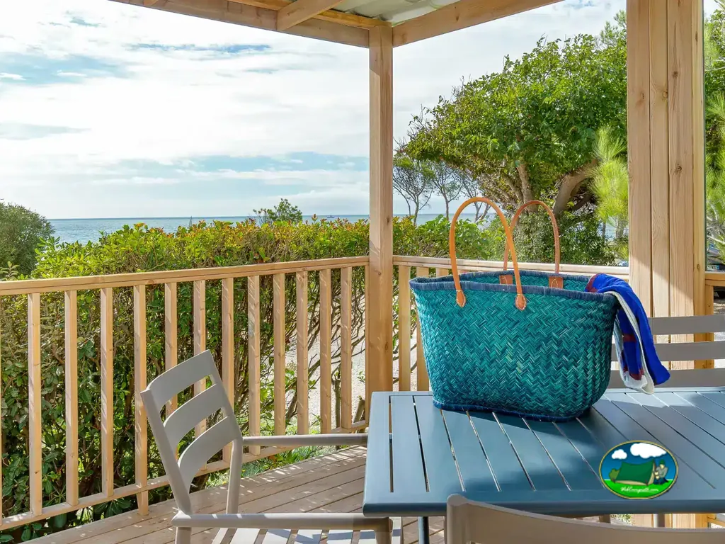 terraza de un mobil-home con vistas al mar y una cesta de playa sobre la mesa en Martigues
