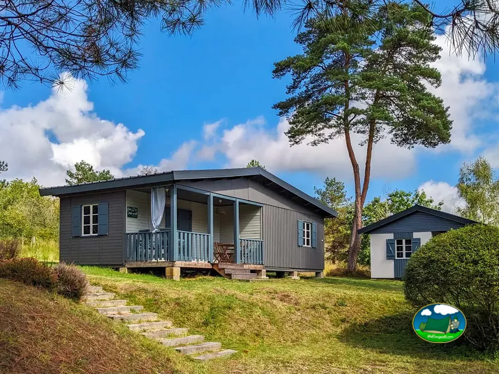 chalet de madera con terraza y otra cabaña al fondo en el camping de Milhac-de-Nontron