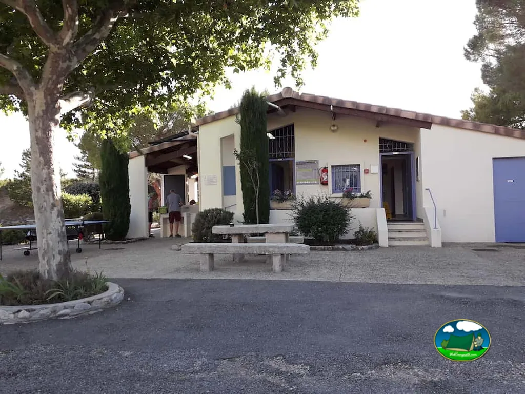 fachada de la recepción con mesa de ping-pong y merenderos de piedra en el camping municipal de Vinsobres