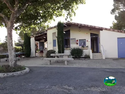 fachada de la recepción con mesa de ping-pong y merenderos de piedra en el camping municipal de Vinsobres