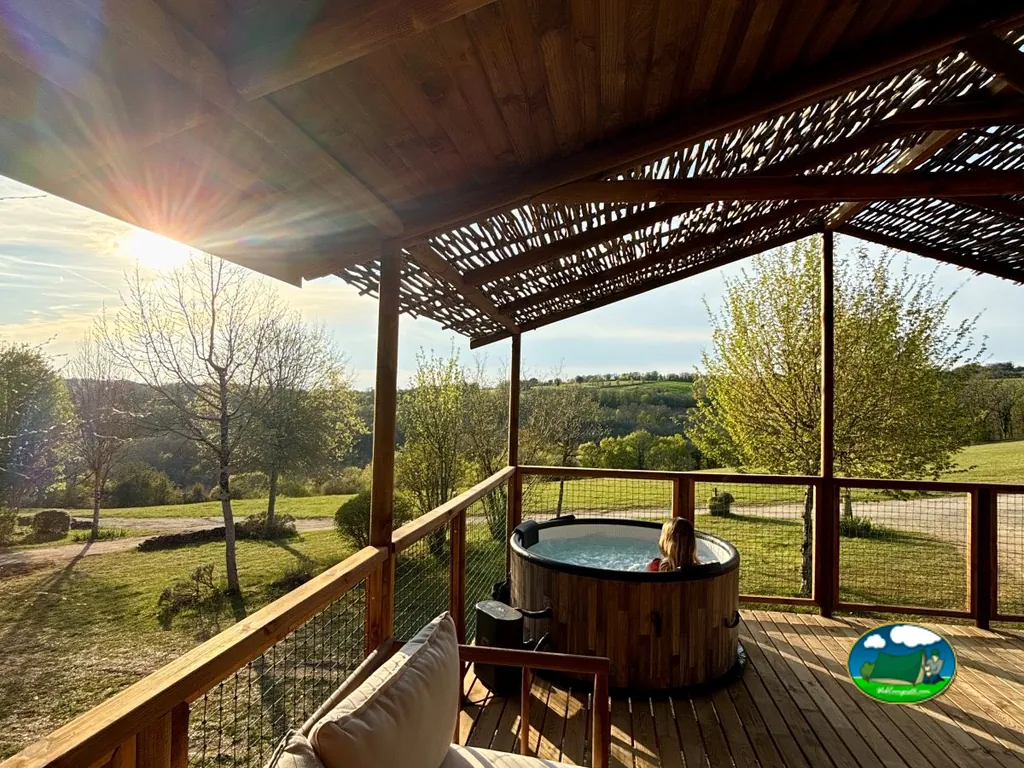 jacuzzi privado en una terraza de madera con vistas al valle al atardecer en Séniergues