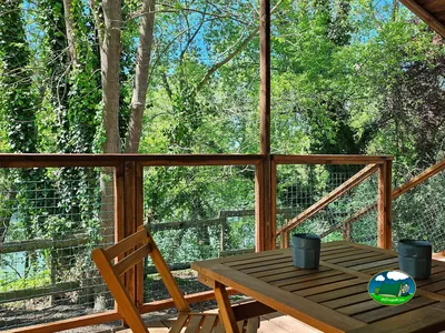 terraza cubierta de madera con mesa entre árboles en el camping de Lescar
