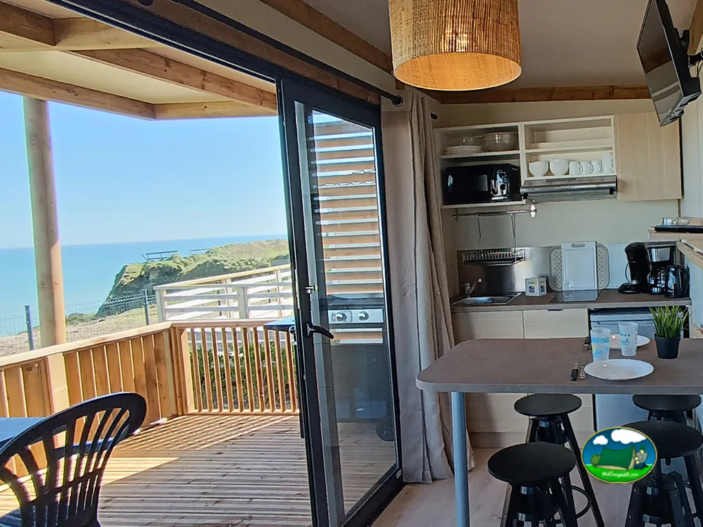 cocina-comedor de un mobil-home con vistas al mar a través de la puerta abierta en Vierville-sur-Mer