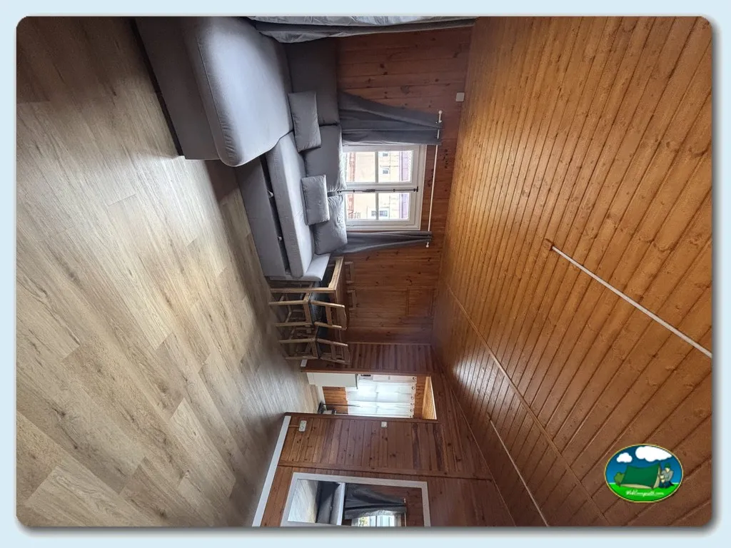 Interior cabaña de madera con cama y ventanas del Camping Deva, Deva. Gijon (Asturias)