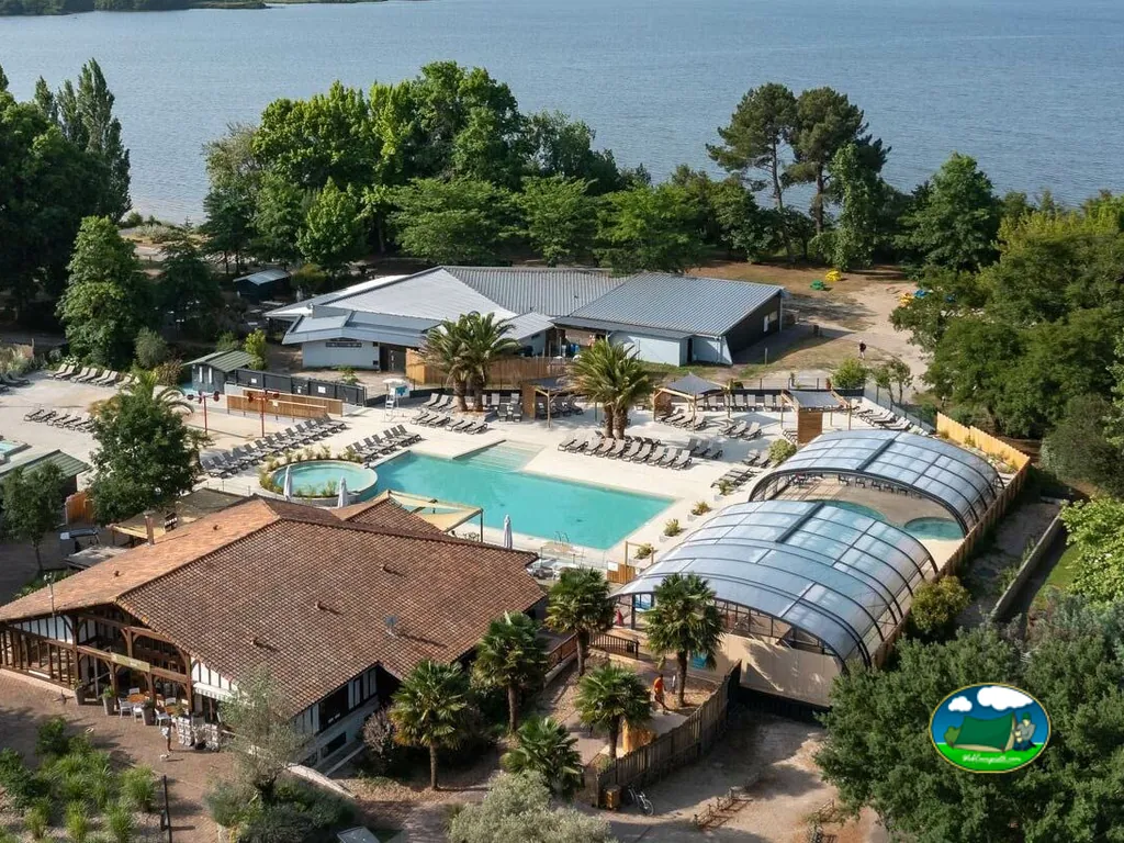 vista aérea del complejo de piscinas y restaurante con techo de tejas junto al lago en Vielle-Saint-Girons