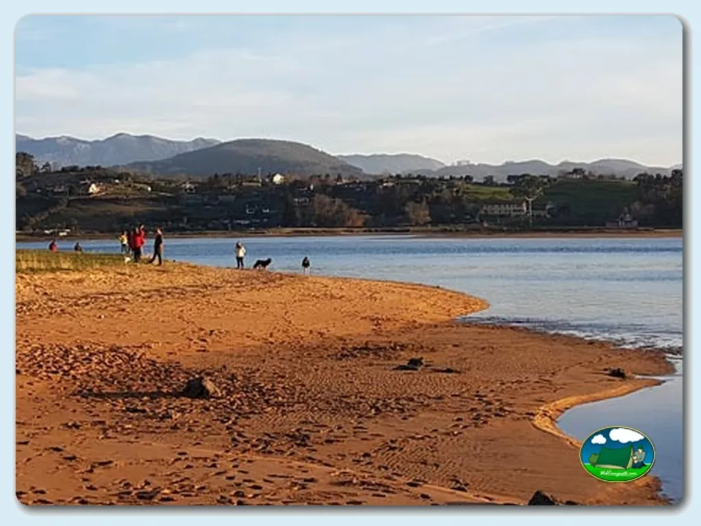 Playa junto al lago con montañas al fondo del Camping Fin de Siglo, Rodiles (Asturias)